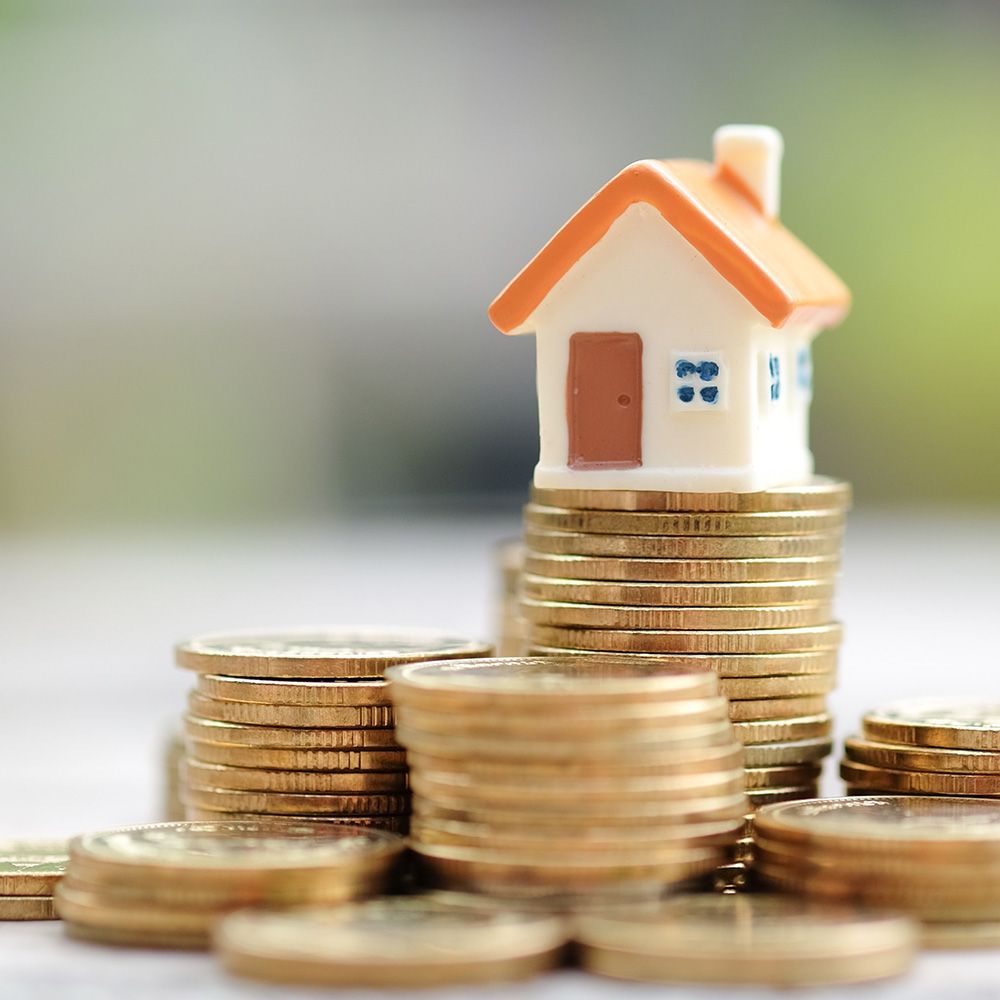 Ein Stapel Kleingeld, wo ein kleines Modellhaus draufsteht.